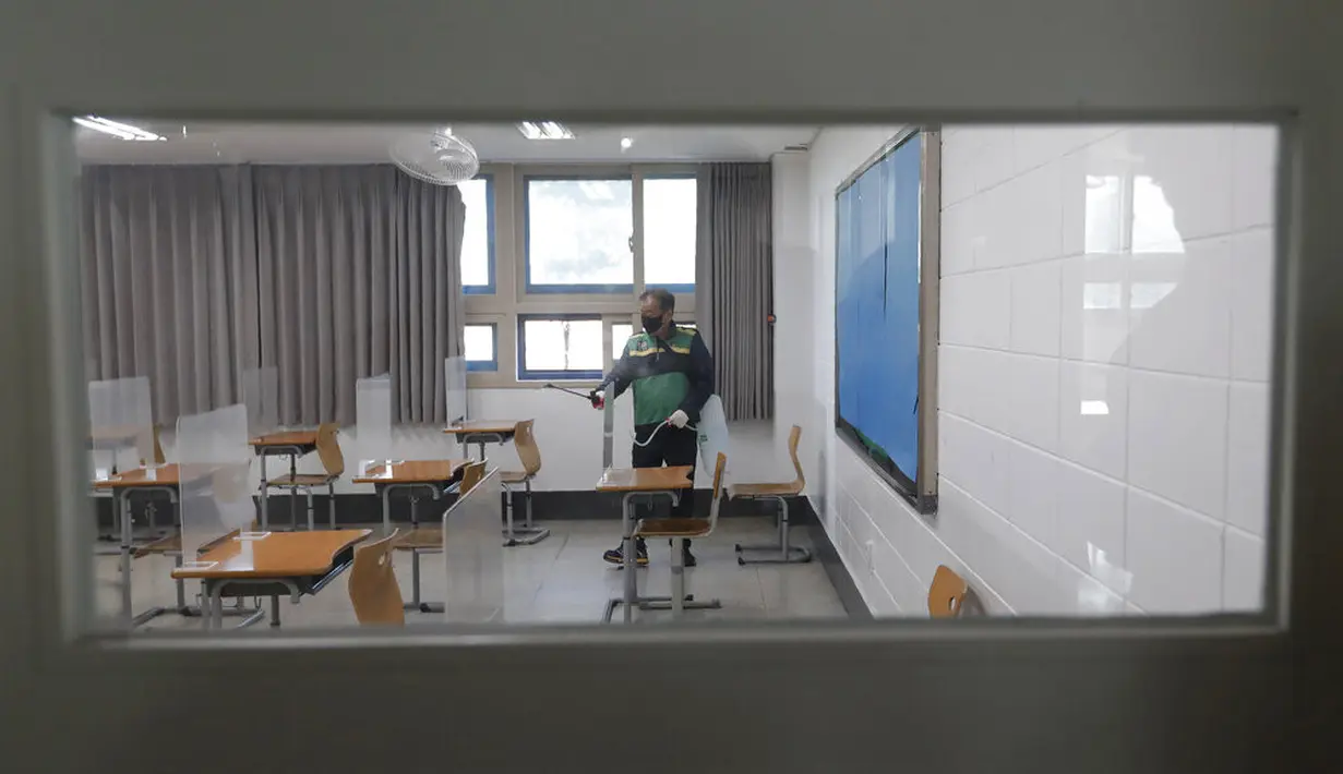 Petugas kesehatan mendisinfeksi ruang kelas untuk ujian masuk perguruan tinggi di Seoul, Korea Selatan, Selasa (1/12/2020). Sekitar 490.000 siswa lulusan sekolah menengah atas di Korea Selatan akan menjalani Tes Kemampuan Skolastik Perguruan Tinggi pada 3 Desember 2020. (AP Photo/Ahn Young-joon)