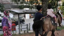 Seorang anak menunggangi kuda di kawasan Kanal Banjir Timur, Jakarta, Selasa (5/6). Berkuda mengelilingi kawasan Kanal Banjir Timur menjadi salah satu pilihan warga untuk ngabuburit sembari mengajak anak-anak bermain. (Merdeka.com/Iqbal S. Nugroho)