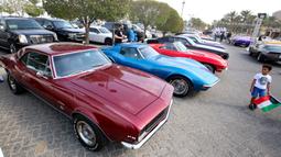 Seorang anak laki-laki menatap mobil klasik Camaro dalam pameran mobil klasik di Marina Crescent, Kuwait City, Kuwait, 29 Oktober 2021. (YASSER AL-ZAYYAT/AFP)
