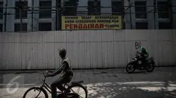 Sejumlah warga melintas di gedung yang sedang direvitalisasi dikawasan Kota Tua, Jakarta, Rabu (20/4). Pekerjaan sudah dimulai sejak tahun 2014.(Liputan6.com/Faizal Fanani)