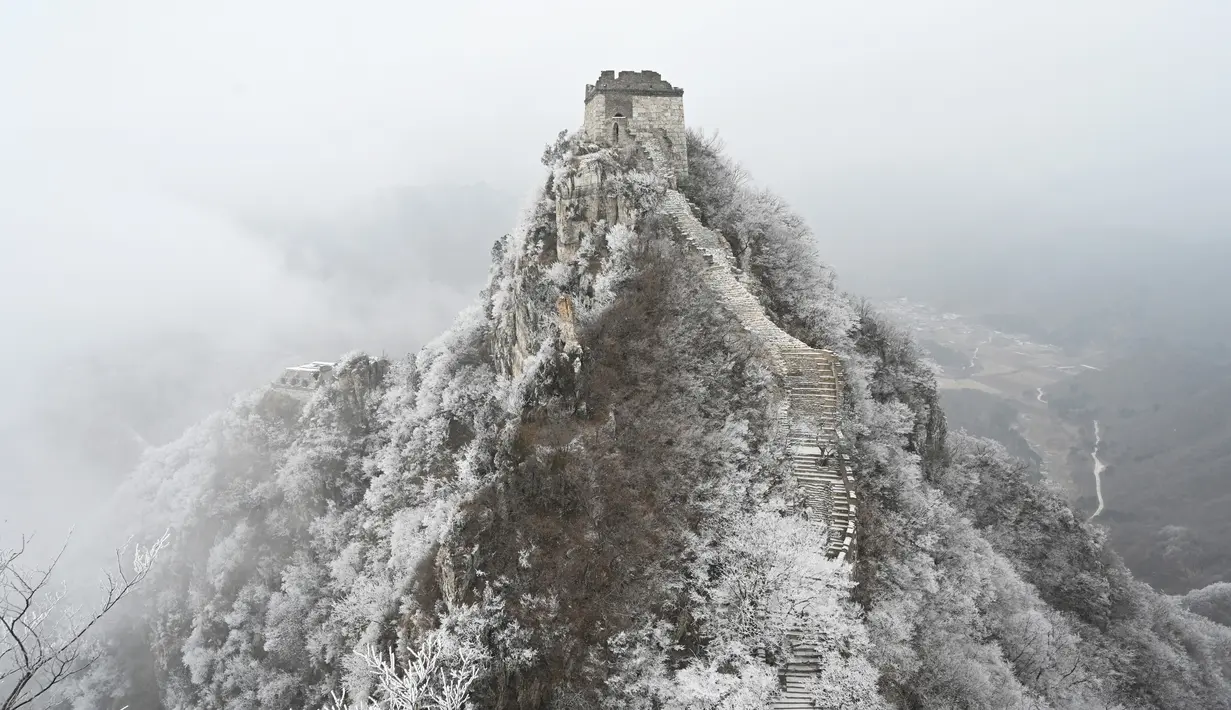 Tembok Besar China terlihat setelah hujan salju ringan di Jiankou, utara Beijing pada Minggu (9/1/2022). Jalur pada Tembok Besar China itu pun terlihat memutih akibat salju. (GREG BAKER / AFP)