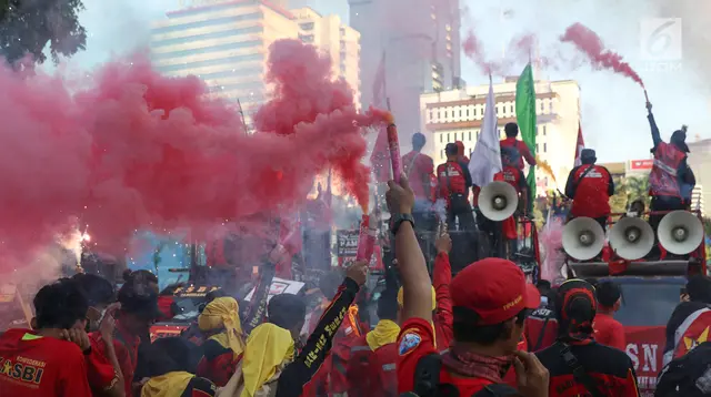 Sejumlah buruh menyalakan bom asap saat menutup aksi Hari Buruh Internasional di Jalan Medan Merdeka Barat, Jakarta, Rabu (5/1/2019). Aksi May Day 2019 di Jakarta ditutup oleh buruh dengan menyalakan kembang api sebagai simbol berjalannya demo dengan damai. (Liputan6.com/Helmi Fithriansyah)