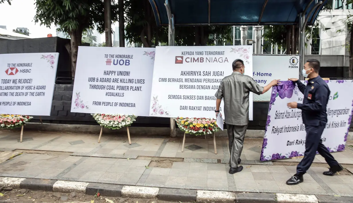 Security menurunkan karangan bunga di depan Kantor Adaro, Jakarta, Senin (3/5/2021). Karangan bunga dikirim sebagai tanda duka cita mendalam karena telah memperparah krisis iklim dengan membiayai produsen batu bara terbesar kedua di Indonesia. (Liputan6.com/Faizal Fanani)