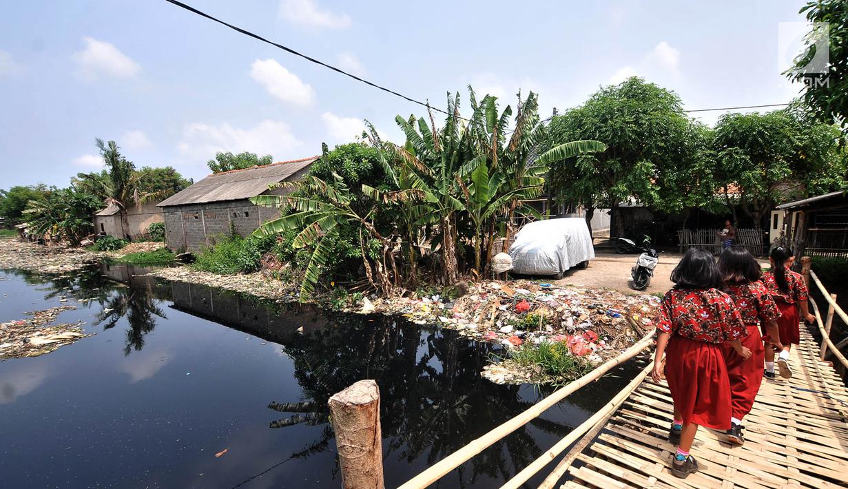 Anak sekolah melintas di pinggir Kali Pisang Batu yang dipenuhi sampah, Tarumajaya, Bekasi, Jawa Barat, Rabu (9/1). Warga tetap beraktivitas meski bau tak sedap menghantui mereka akibat tumpukan sampah di kali tersebut. (Merdeka.com/Iqbal S. Nugroho)