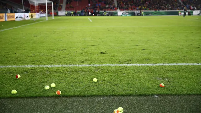 Suporter Borussia Dortmund melemparkan bola tenis ke tengah lapangan.