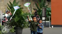 Dua orang anak berusaha menerbangkan layang layang saat bermain di Lapangan Monumen Tugu Pancasila TMII, Jakarta, Jumat (8/7). TMII masih menjadi lokasi favorit warga menghabiskan libur hari raya. (Liputan6.com/Helmi Fithriansyah)