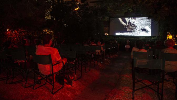Penonton menonton film di bioskop terbuka Oasis, Athena, Yunani, 1 Agustus 2020. Pandemi COVID-19 memaksa bioskop terbuka dipersingkat sehingga menyebabkan penurunan jumlah penonton. (ANGELOS TZORTZINIS/AFP)