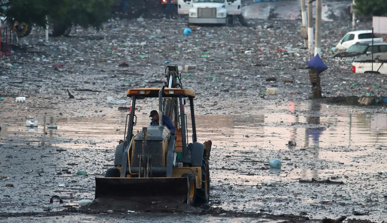 Sebuah ekskavator bekerja di jalan berlumpur setelah hujan lebat meluap ke aliran El Seco di Zapopan, Jalisco State, Meksiko, Senin (26/7/2021). Luapan sungai menyebabkan banjir disertai lumpur dan sampah melanda Zapopan, kota di negara bagian Jalisco, Meksiko. (AFP/Ulises Ruiz)