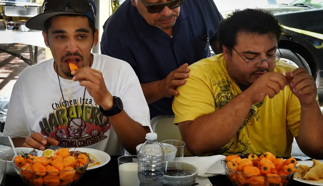 Dua orang peserta mencoba menyelesaikan makan cabai Habanero dalam Habanero Eating Contest di Restoran Chichen Itza, Los Angeles, Minggu (21/6). Dalam lomba ini setiap peserta diberikan 60 cabai Habanero dengan waktu 20 menit. (AFP PHOTO/Mark RALSTON)