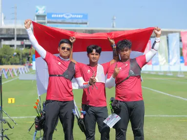 Tim panahan Indonesia, Riau Ega Agata Salsabilla, Ahmad Khoirul Baasith dan Arif Dwi Pangestu (kiri ke kanan) memegang bendera Merah Putih usai memenangi nomor recurve beregu putra SEA Games 2025 di Football Field 1, Bangkok, Thailand, Rabu (17/12/2025). Indonesia kembali menambah koleksi raihan medali emas SEA Games 2025 Thailand. (Bola.com/Bagaskara Lazuardi)