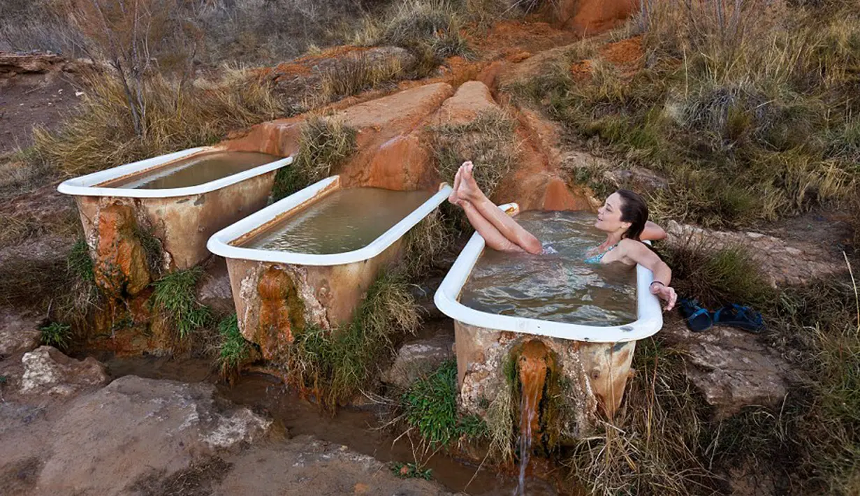 Seorang pengunjung bersantai di bak mandi yang berada di Mystic Hot Springs di Utah, Amerika Serikat. Bak mandi yang terletak di bukit ini sengaja dipasang oleh Mike Ginsburg yang saat itu sedang berlibur ketempat ini. (Dailymail.co.uk)