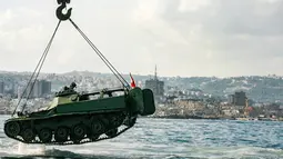 Aktivis lingkungan menurunkan tank lama ke dasar Laut Mediterania di lepas pantai kota pelabuhan Sidon, Lebanon, Sabtu (28/7). Para aktivis berharap rumput laut akan segera menutupi tank, yang merupakan hadiah dari militer tersebut. (AFP / Mahmoud ZAYYAT)