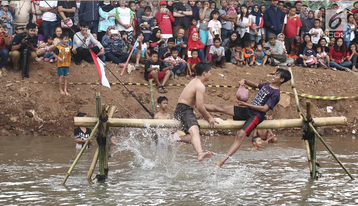 Dua peserta berusaha saling menjatuhkan saat mengikuti lomba gebuk bantal dalam Festival Kalimalang di Cipinang Melayu, Jakarta Timur, Kamis (17/8). Festival Kalimalang ini dalam rangka memeriahkan HUT ke-72 RI. (Liputan6.com/Herman Zakharia)