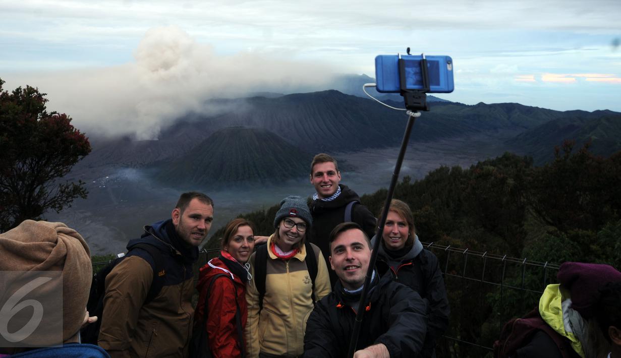 Wisatawan asing berfoto berlatar erupsi Gunung Bromo di Puncak Penanjakan Taman Nasional Bromo Tengger Semeru, Jawa Timur, Kamis (21/7). Meski berstatus waspada, intensitas kunjungan ke Gunung Bromo justru meningkat. (Liputan6.com/Helmi Fithriansyah)
