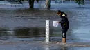 Seorang remaja mencari ikan saat banjir melanda Kota Forbes, kawasan pedalaman di New South Wales, Australia, Selasa (27/9). Sungai Lachlan meluap karena tak sanggup menampung air yang berlimpah akibat hujan deras. (REUTERS / Jason Reed)