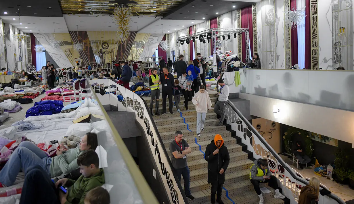 Relawan membantu pengungsi yang melarikan diri dari invasi Rusia dari negara tetangga Ukraina duduk di dalam ballroom yang diubah menjadi tempat penampungan pengungsi darurat di hotel & spa bintang 4, di Suceava, Rumania, 4 Maret 2022. (AP Photo/Andreea Alexandru)
