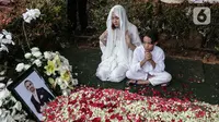 Bunga Citra Lestari atau BCL bersama anaknya Noah Sinclair duduk di samping makam Ashraf Sinclair di San Diego Hills, Karawang, Jawa Barat, Selasa (18/2/2020). Keluarga dan kerabat mengiringi pemakaman jenazah Ashraf Sinclair. (Liputan6.com/Faizal Fanani)