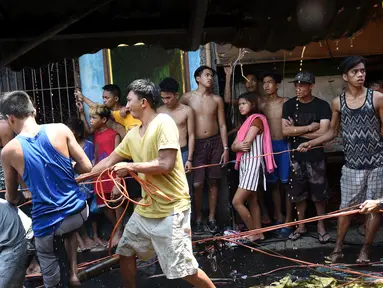 Sejumlah warga mencoba mengambil sisa kabel listrik saat insiden kebakaran sebuah pemukiman padat penduduk dekat pelabuhan di Manila, Filipina, Selasa (9/5). Mereka berebut mengumpulkan tembaga dari sisa kabel listrik. (TED ALJIBE/AFP)