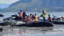 Sejumlah relawan menyiramkan air dan berusaha menarik ke tengah pantai untuk menyelamatkan ikan paus pilot yang terdampar di Farewell Spit, Selandia Baru (11/2). (AFP/Marty Melville)