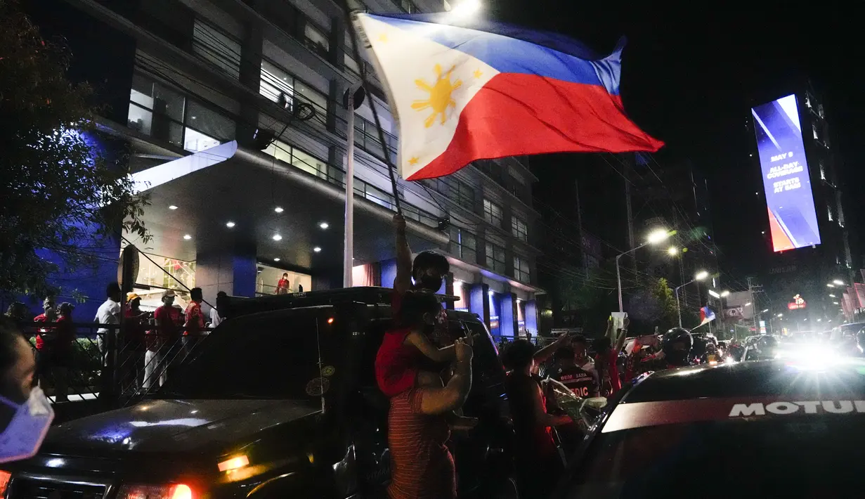 <p>Seorang pendukung mengibarkan bendera saat mereka tiba di markas besar Ferdinand "Bongbong" Marcos Jr di Mandaluyong, Filipina pada Senin malam (9/5/2022). Ferdinand Marcos Jr., putra mendiang Ferdinand Marcos, diktator Filipina yang terguling, jauh memimpin dalam penghitungan suara tidak resmi pemilu presiden hari Senin. (AP Photo/Aaron Favila)</p>