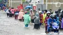 Sejumlah pengendara dan warga melintasi banjir di Jalan Raya Bekasi, Jakarta Timur, Selasa (25/2/2020). Banjir akibat hujan yang melanda Bekasi sejak Selasa (25/2) dini hari memutus beberapa titik jalan raya di wilayah setempat. (merdeka.com/Imam Buhori)
