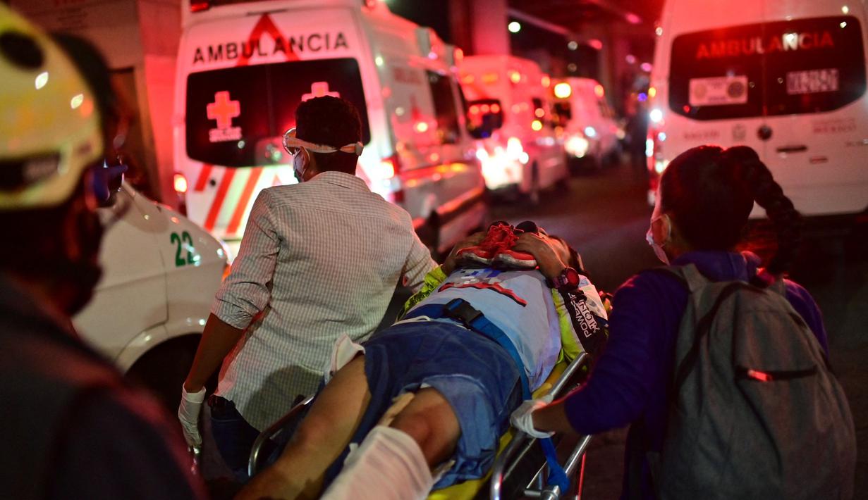 Pekerja darurat membawa orang yang terluka dengan tandu setelah jembatan layang untuk kereta metro ambruk di Mexico City, Senin (3/5/2021). Setidaknya 13 orang tewas dan puluhan lainnya luka-luka akibat kecelakaan kereta metro di ibu kota Meksiko tersebut. (Pedro PARDO/AFP)