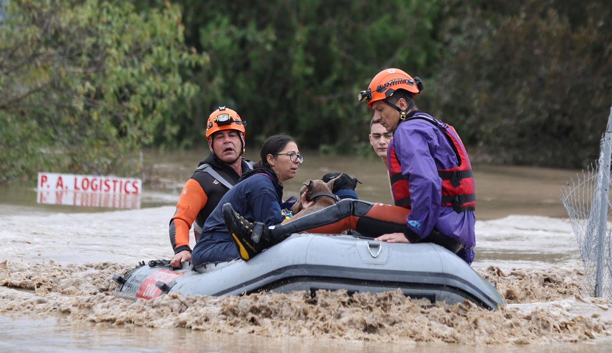 Petugas pemadam kebakaran dengan perahu karet mengevakuasi orang-orang dan hewan peliharaan dari sebuah bangunan yang terendam banjir di Larissa, Yunani Tengah, Rabu, 6 September 2023. (AP Photo/Vaggelis Kousioras)