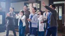 Dalam potongan gambar terbaru yang dirilis oleh SBS, tampak kehadiran Kang Dong Joo sang dokter bedah umum yang disambut hangat oleh keluarga besar rumah sakit Doldam. Mereka tersenyum dengan mata berbinar. (Foto: SBS via Soompi)