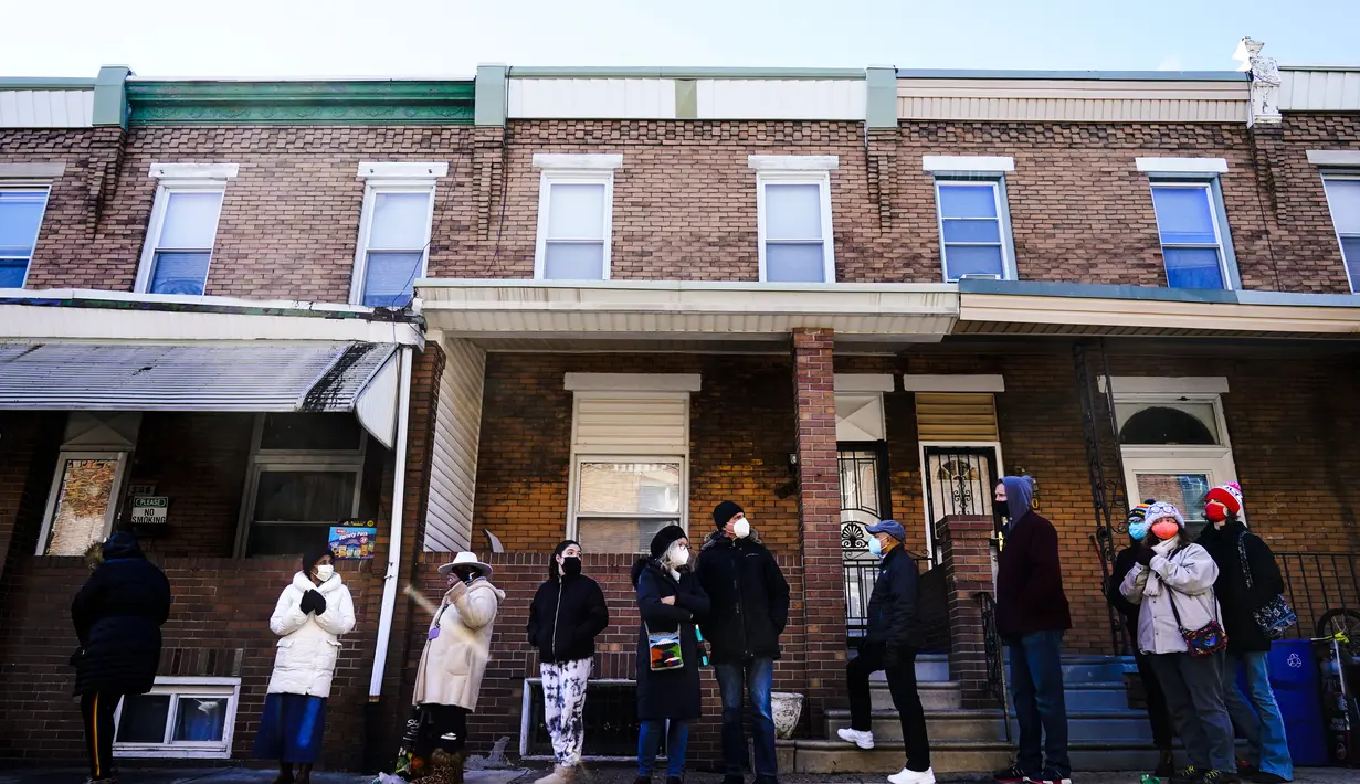 Antrean warga kota di sepanjang blok untuk menerima alat tes cepat COVID-19 di rumah secara gratis di Philadelphia, Senin (20/12/2021). Philadelphia membagikan tes COVID cepat yang bisa dipakai di rumah secara gratis hingga Natal mendatang. (AP Photo/Matt Rourke)