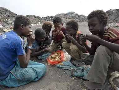 Sejumlah anak laki-laki makan bersama usai mengumpulkan sampah untuk didaur ulang di tempat pembuangan sampah di kota Houdieda, Yaman, Rabu (20/1). (REUTERS/Abduljabbar Zeyad)