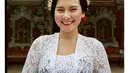 Indah Permatasari bak gadis Bali dibalut kebaya putih. Kebaya brokat sederhana berwarna putih dipadunya dengan selendang ungu yang diikatkannya di bagian perut. Indah bahkan menyempurnakan penampilannya dengan gaya rambut ikonis; sanggul dan hiasan bunganya. [Foto: Instagram/indahpermatas]