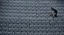 Seorang pria menyapu tribun selama turnamen tenis Italia Terbuka di Foro Italico, Roma, Selasa (10/5/2021). Pertandingan tersebut dimainkan tanpa penonto karena pembatasan COVID-19. (Filippo MONTEFORTE / AFP)