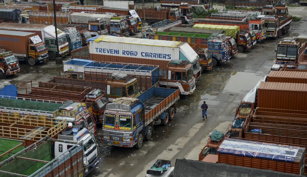 Seorang pria berjalan melewati truk-truk yang diparkir di sebuah terminal di Chennai (19/9/2019). Layanan transportasi darat menyerukan pemogokan satu hari untuk memprotes kenaikan pinalti di bawah Undang-undang Kendaraan Bermotor (Amandemen) yang baru. (AFP Photo/Arun Sankar)