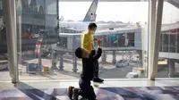Seorang anak yang mengenakan masker bermain dengan anak laki-laki lain di Bandara Internasional Hong Kong di Hong Kong, Selasa (21/1/2020). Masker terjual habis dan pemeriksaan suhu di bandara dan stasiun kereta api menjadi norma baru di China menyusul merebaknya wabah virus corona. (AP/Ng Han Guan)
