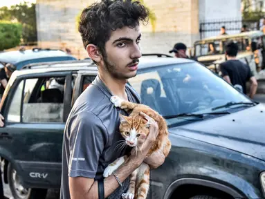 Seorang pemuda memeluk seekor kucing di dadanya saat orang-orang yang melarikan diri dari desa mereka di Lebanon selatan diterima di sebuah lembaga seni yang diubah menjadi tempat penampungan bagi para pengungsi akibat konflik, di Beirut pada 23 September 2024. (FADEL ITANI/AFP)
