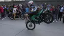Pengendara sepeda motor dan penumpangnya melakukan wheelie di sepeda motornya selama pameran di lingkungan El Valle Caracas, Venezuela, Sabtu (31/7/2021). (AP Photo/Ariana Cubillos)