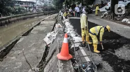 Petugas Sudin Bina Marga Jakarta Pusat memperbaiki jalan ambles di Jalan Inspeksi Kali Ciliwung, Kenari, Rabu (19/1/2022). Jalan yang berada di belakang RSCM tersebut ambles sepanjang 40 meter akibat terkikis oleh hujan deras kemarin sehingga menyulitkan akses warga. (merdeka.com/Iqbal S Nugroho)