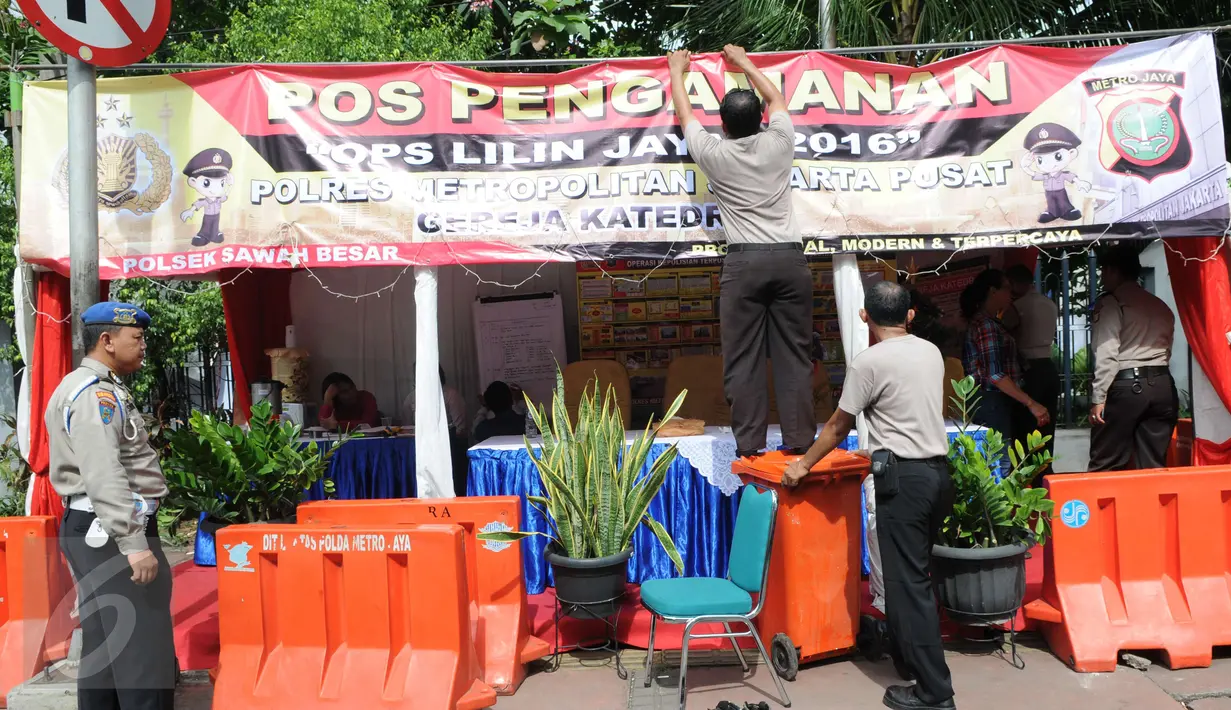 Petugas memasang spanduk di posko penjagaan Gereja Katedral, Jakarta, Sabtu (24/12). Penjagaan dilakukan untuk menjaga kondusifitas agar acara Malam Misa Natal bisa berjalan lancar. (Liputan6.com/Helmi Afandi) 