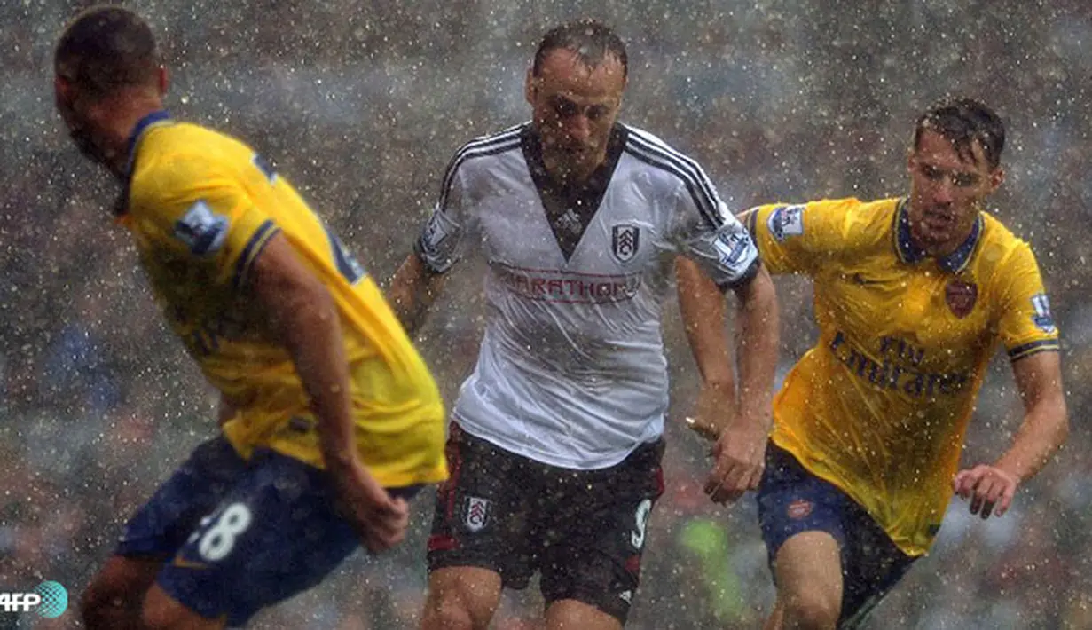 Dimitar Berbatov manghadapi hadangan bek Arsenal di bawah guyuran hujan pada pertandingan Liga Inggris antara Fulham melawan Arsenal di Stadion Craven Cottage, London Sabtu 24 Agustus 2013. (AFP/Carl Court)