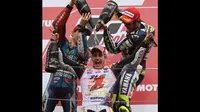 Pembalap Yamaha MotoGP, Jorge Lorenzo (kiri) dan Valentino Rossi mengguyurkan sampanye ke Marc Marquez di podium kemenangan di Sirkuit Motegi, Jepang, (12/10/2014). (AFP PHOTO/Toshifumi Kitamura)