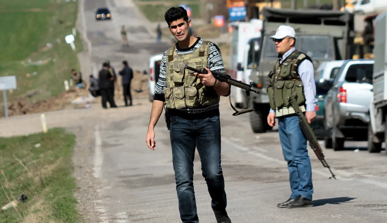Petugas keamanan berjaga disekitaran terjadinya serangan bom remote kontrol di Diyarbakir, Turki (18/2). Bom tersebut menghantam kendaraan lapis baja milik militer Turki. (REUTERS / Sertac kayar)
