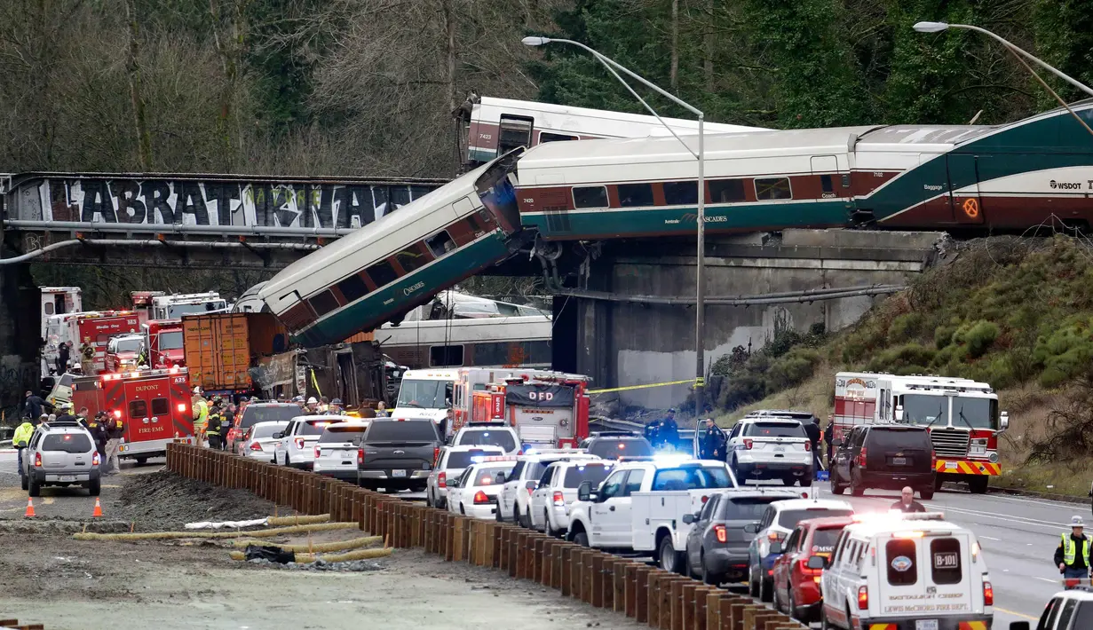 Kereta Amtrak yang terjatuh dari jembatan dan menimpa kendaraan-kendaraan terlihat di jalan raya di Interstate di DuPont, Washington, AS (18/12). Diketahui 13 dari 14 gerbong kereta jatuh ke jalan raya. (AP Photo / Elaine Thompson)