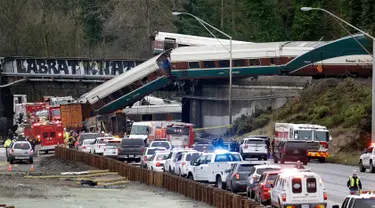 Kereta Amtrak yang terjatuh dari jembatan dan menimpa kendaraan-kendaraan terlihat di jalan raya di Interstate di DuPont, Washington, AS (18/12). Diketahui 13 dari 14 gerbong kereta jatuh ke jalan raya. (AP Photo / Elaine Thompson)