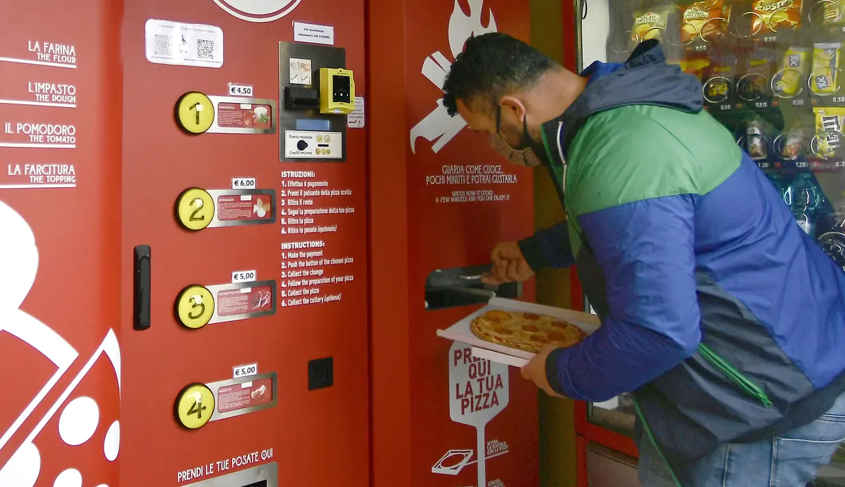 Seorang pria mengambil pesanannya di mesin penjual pizza otomatis, yang pertama dari jenisnya di pusat kota Roma, pada 29 April 2021. Mesin penjual otomatis ini mampu menguleni adonan, membumbui, memasak, dan menyajikan pizza dalam kotak karton hanya dalam waktu tiga menit. (Filippo MONTEFORTE/AFP)