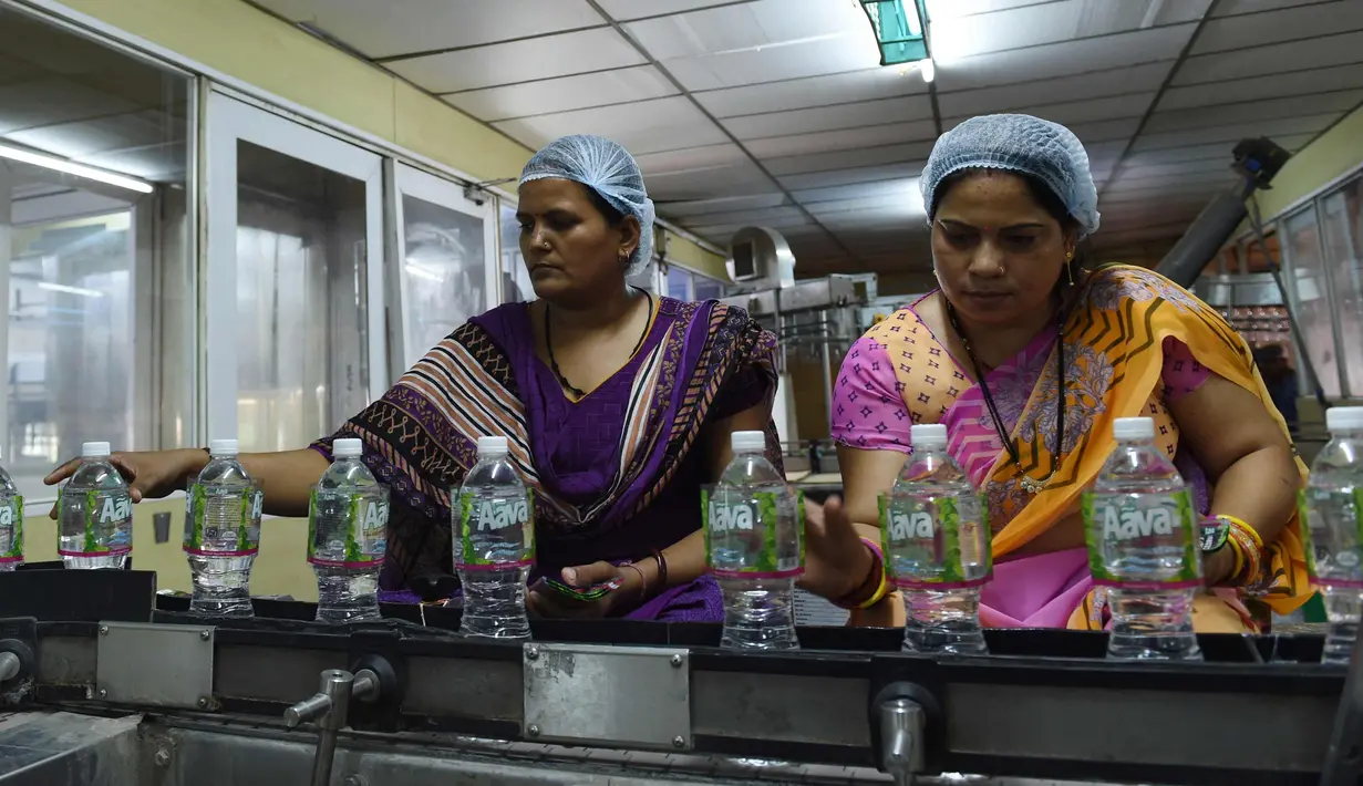 Pekerja menempelkan label botol air mineral alami Aava di Ahmedabad, India (19/3). Hari Air Sedunia jatuh pada tanggal 22 Maret dan berfokus pada pentingnya akses universal terhadap air bersih, sanitasi dan fasilitas kebersihan. (AFP Photo/Sam Panthaky)
