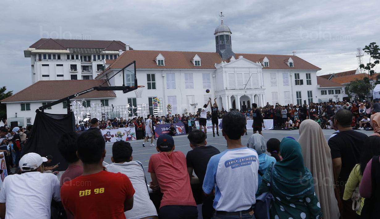 Warga menyaksikan pertandingan basket 3x3 pada acara Asian Games Sport Festival di Taman Fatahilah, Jakarta, Sabtu (9/12/2017). Acara tersebut bertujuan untuk mempromosikan Asian Games 2018. (Bola.com/M Iqbal Ichsan)