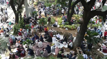 Massa aksi duduk-duduk beristirahat di taman pembatas Jalan Medan Merdeka Barat, Jakarta, Kamis (27/6/2019). Massa aksi berkumpul terkait pelaksanaan sidang putusan perselisihan hasil Pilpres 2019 di Gedung Mahkamah Konstitusi. (Liputan6.com/Helmi Fithriansyah)