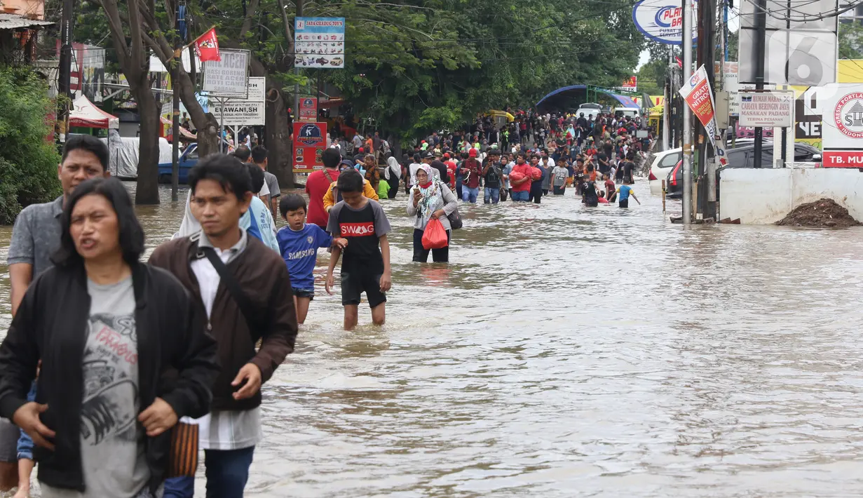 Warga melintasi banjir yang menggenangi Jalan KH Hasyim Ashari, Tangerang, Banten, Kamis (2/1/2020).Banjir yang menggenangi jalan penghubung Jakarta- Tangerang tersebut mulai surut dan sudah bisa dilintasi pejalan kaki. (Liputan6.com/Angga Yuniar)