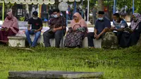 Orang-orang berdoa saat peringatan 16 tahun gempa bumi dan tsunami Aceh di sebuah kuburan massal di Siron, Sabtu (26/12/2020).  Peringatan di tengah pandemi COVID-19 itu tetap berlangsung secara sederhana melalui kegiatan ziarah kubur. (CHAIDEER MAHYUDDIN/AFP)