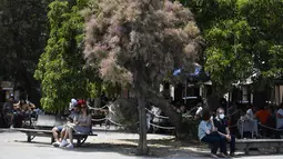 Orang-orang duduk di kawasan pejalan kaki di Pantai Barceloneta, Barcelona, Minggu (6/6/2021). Spanyol akan mengizinkan semua pelancong yang divaksinasi untuk mengunjungi negara itu mulai 7 Juni, dengan tujuan kembali menghidupkan industri perjalanan yang terpukul pandemi Covid-19. (Pau BARRENA/AFP)